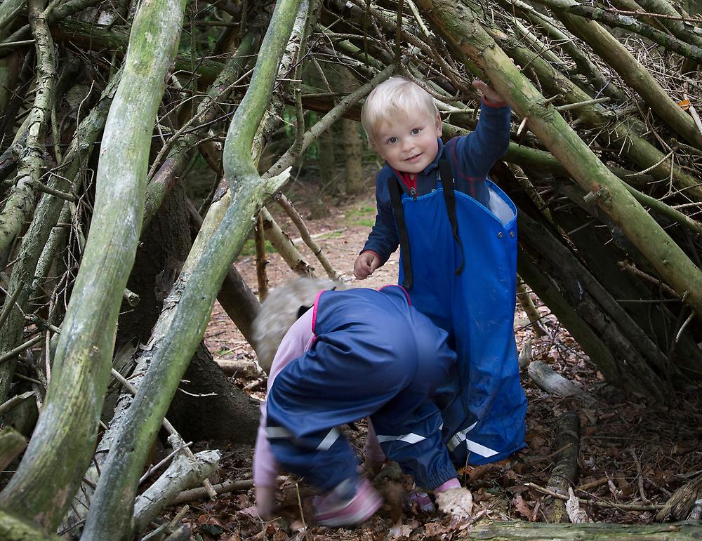 Två barn leker i koja i skogen
