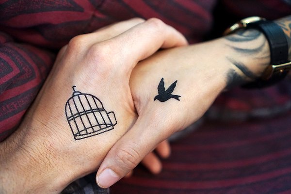 Två tatuerade händer som tar varann i hand